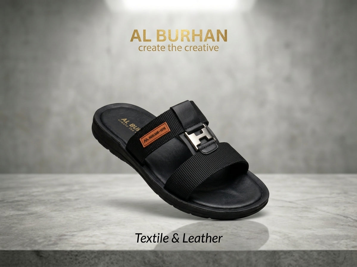 Black leather and textile slide sandal with H-shaped buckle on grey stone surface